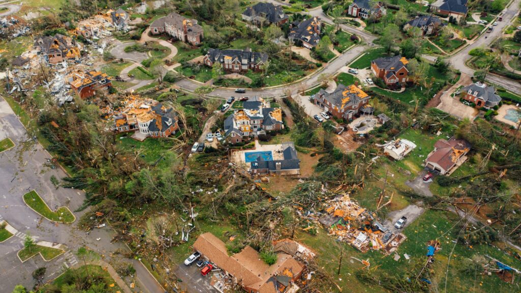 Aerial view of houses damaged by a storm, with debris across the neighborhood